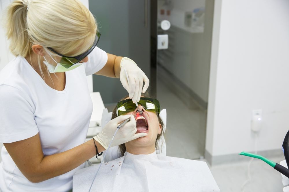 Laser Gum Treatment Procedure – Oakville Dental Periodontal Care Dental professional performing laser gum treatment on a patient wearing protective eyewear at Oakville Dental