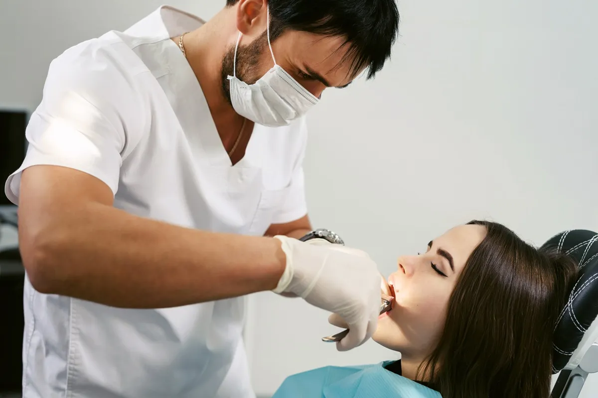 Dentist performing a tooth extraction procedure on a patient at Oakville Dental clinic